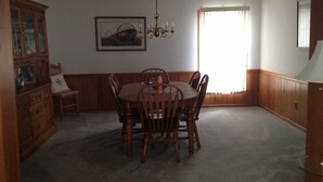 A dining room with a wooden table and chairs, a chandelier, a cabinet with glass doors, and a window with blinds. - Quiet Waterfront House Sleeps10, Plenty Of Parking, Boat Slip (Rehoboth Beach)
