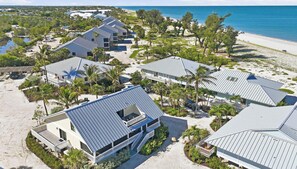 Een hotel aan de kust met meerdere gebouwen, een strand en palmbomen.