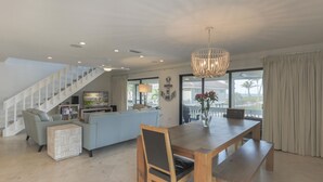 Un espacio habitable amplio con una mesa de comedor de madera, un sofá y una escalera.