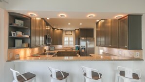 Una cocina moderna con armarios de madera oscura, una isla central con taburetes de bar y electrodomésticos integrados.