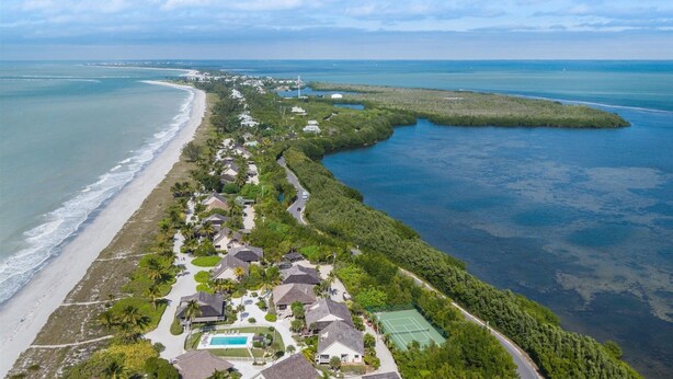 Vista aérea de una zona residencial costera con casas, una playa y una vista despejada del océano.