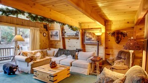 L’intérieur chaleureux d’un chalet, avec un décor en bois, un canapé, un fauteuil, une petite table et une statue d’ours.