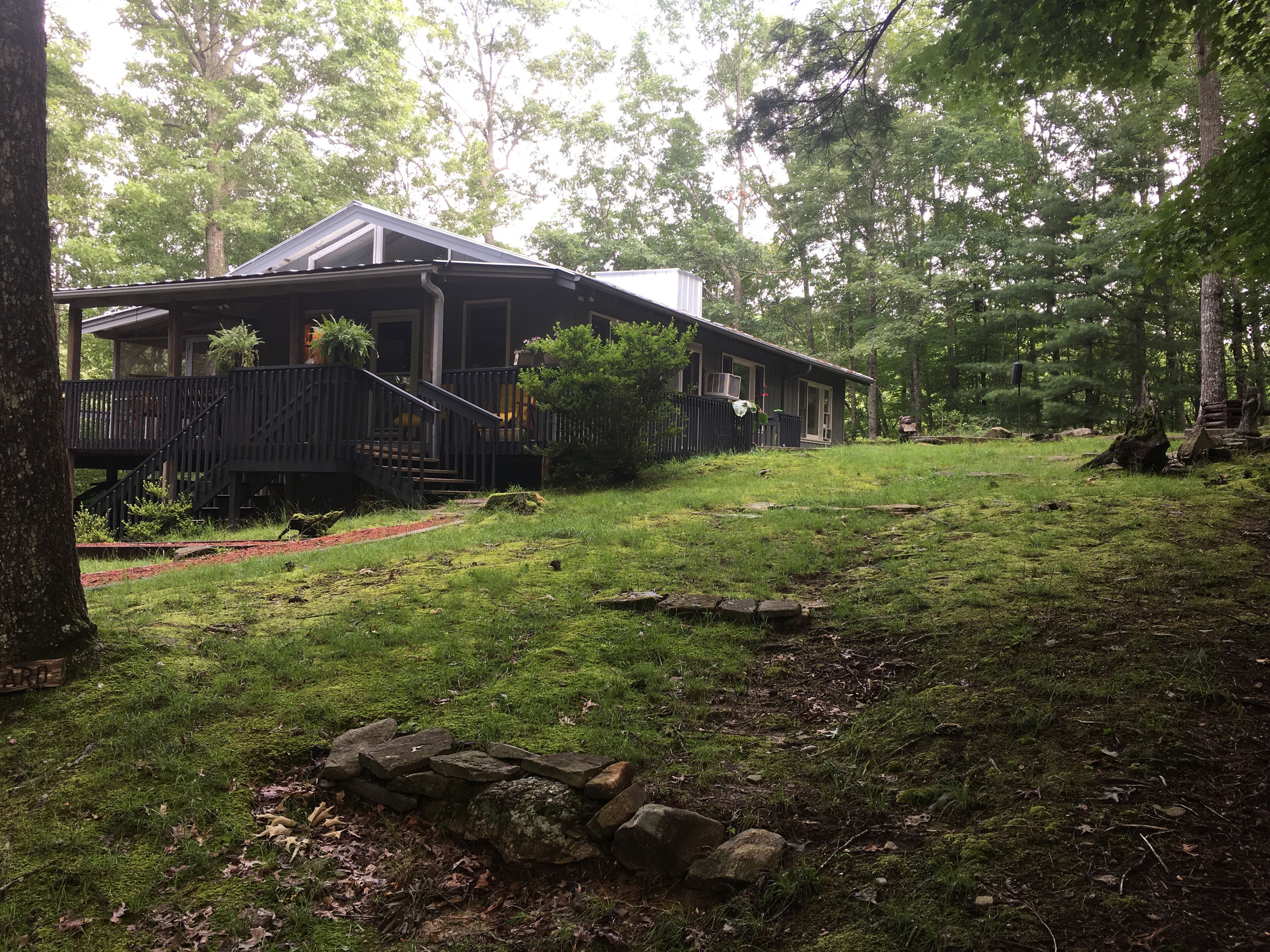 A rustic cabin with a wooden deck and stairs leading to a porch.