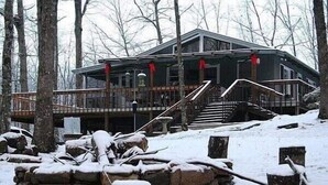 Une cabane dotée d’un porche abrité, d’un escalier et surplombant un paysage enneigé.