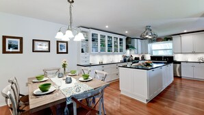 Une cuisine moderne avec des meubles blancs, une table à manger en bois et un îlot central.