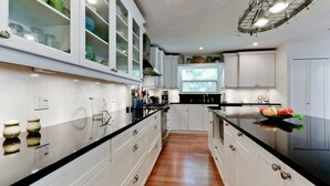 Une cuisine moderne avec des meubles blancs, un plan de travail noir et une fenêtre qui laisse entrer la lumière naturelle.