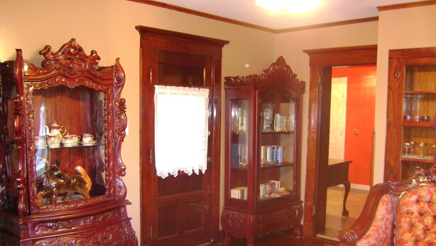 A traditional living room with ornate wooden furniture, including a large mirror, a bookcase, and a dining table. - Room #6 We are only 30 min. away from  "BASEBALL HALL OF FAME" in Coopers Town . (Fort Plain)