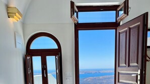 Un dormitorio con cama, cómoda, ventana con puerta abierta y vista al litoral.
