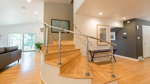 Un intérieur moderne avec un escalier à volutes, un plancher en bois et un mur gris orné d’œuvres d’art.