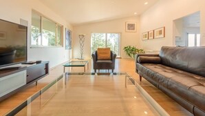 Un salon moderne avec un canapé en cuir, une table basse en verre et un téléviseur à écran plat.