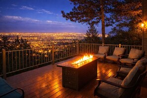 A deck with a fire pit and outdoor seating, overlooking a cityscape at dusk. - Luxury 4,000 sf Canyon Estate Views near Broadmoor (Colorado Springs)