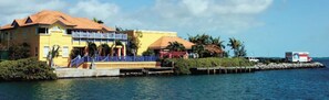 A waterfront property with a yellow building, a blue staircase, and a dock extending into the water. - Real World MTV House-18 to 22 guests, Not Just a  House Your Own Private Resort (Key West)