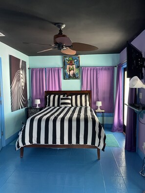 A bedroom with a large bed, a ceiling fan, purple curtains, and artwork on the walls. - Real World MTV House-18 to 22 guests, Not Just a  House Your Own Private Resort (Key West)