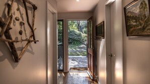 Un pasillo con piso de madera que conduce a una puerta de cristal que da a un jardín.