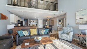 A spacious living area with a black leather sofa, a patterned armchair, and a wooden coffee table. A dining area with a wooden table and chairs is visible in the background. - Condo perfect for families and friends!!! (Camdenton)