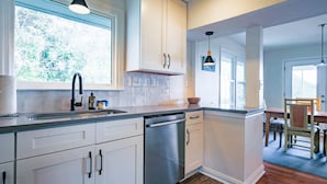 Een moderne keuken met witte kasten, een roestvrijstalen vaatwasser en een raam voor natuurlijk licht.