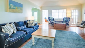 Een woonkamer met een blauwe bank, een houten salontafel en twee fauteuils.