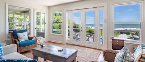 Amplia sala de estar con vista al océano, amueblada con mobiliario de mimbre y una mesa de centro de madera.