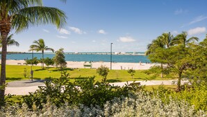 A beachside park with palm trees, a sandy area, and a view of the ocean.