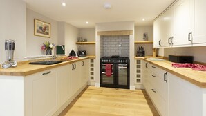 Una cocina moderna con armarios blancos, estufa negra y encimeras de madera.