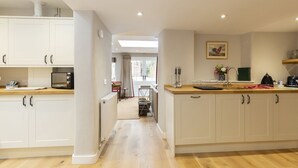 Una cocina moderna con armarios blancos, encimera de madera y vistas al comedor.