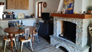 A cozy kitchen with wooden cabinets, a stone fireplace, and a dining area with a table and chairs.