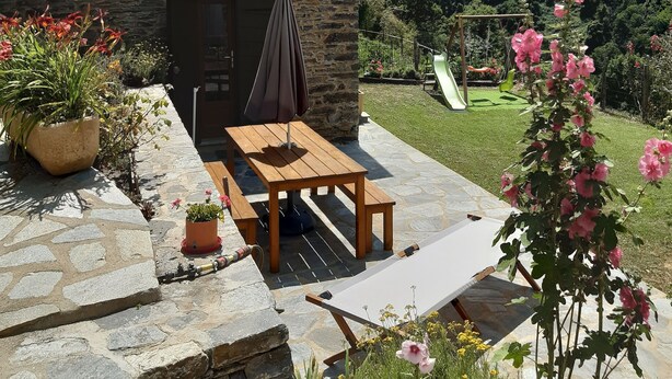 A stone building with a patio, a wooden table, and a bench.