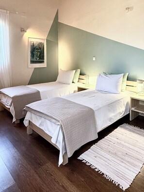 Habitación de hotel con dos camas, una mesita de noche, una lámpara, un cuadro y una alfombra.