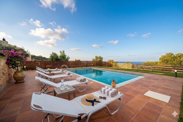 Un área junto a la piscina con sillones de descanso, piscina y vistas al paisaje.