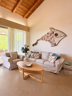A living room with a wooden ceiling, a sofa set, a coffee table, and a wall-mounted fish decoration.