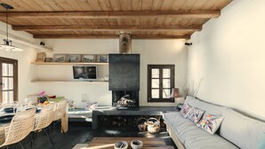 Een gezellige woonkamer met een open haard, houten plafond en een bank met kleurrijke kussens.