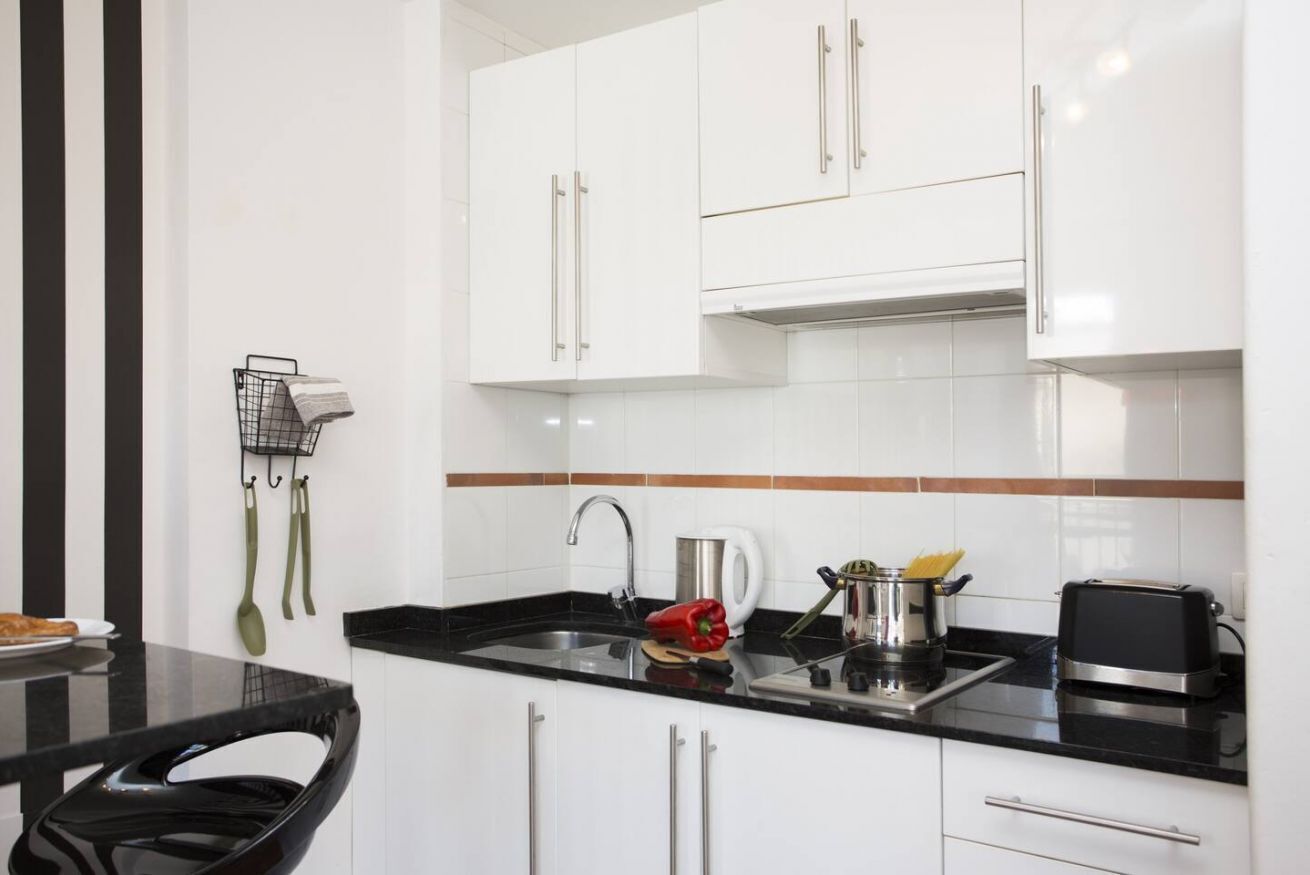 Een moderne keuken met witte kasten, een zwart aanrecht en roestvrijstalen apparatuur.