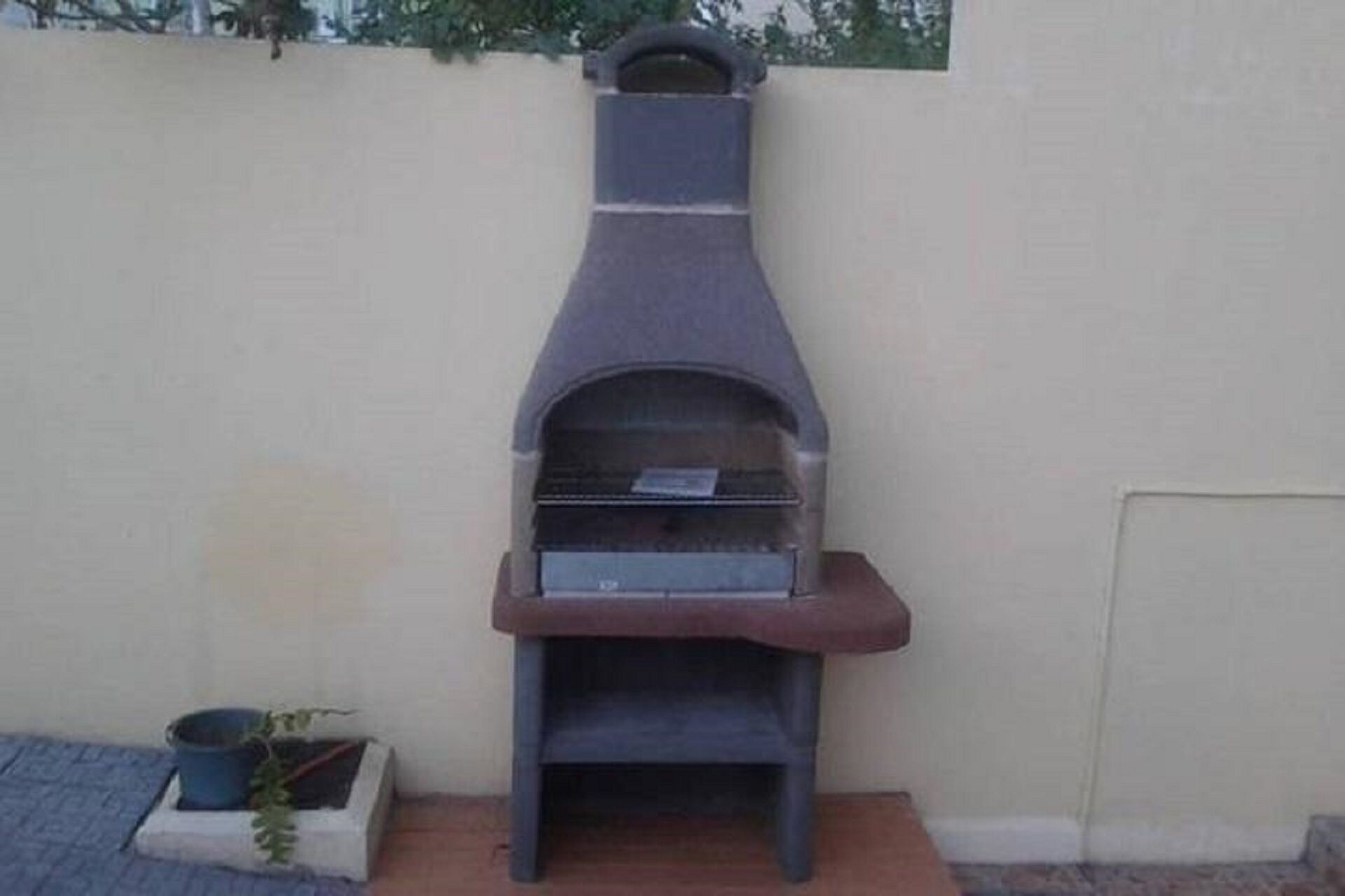 Un pequeño horno de pizza al aire libre, apoyado en una pared.