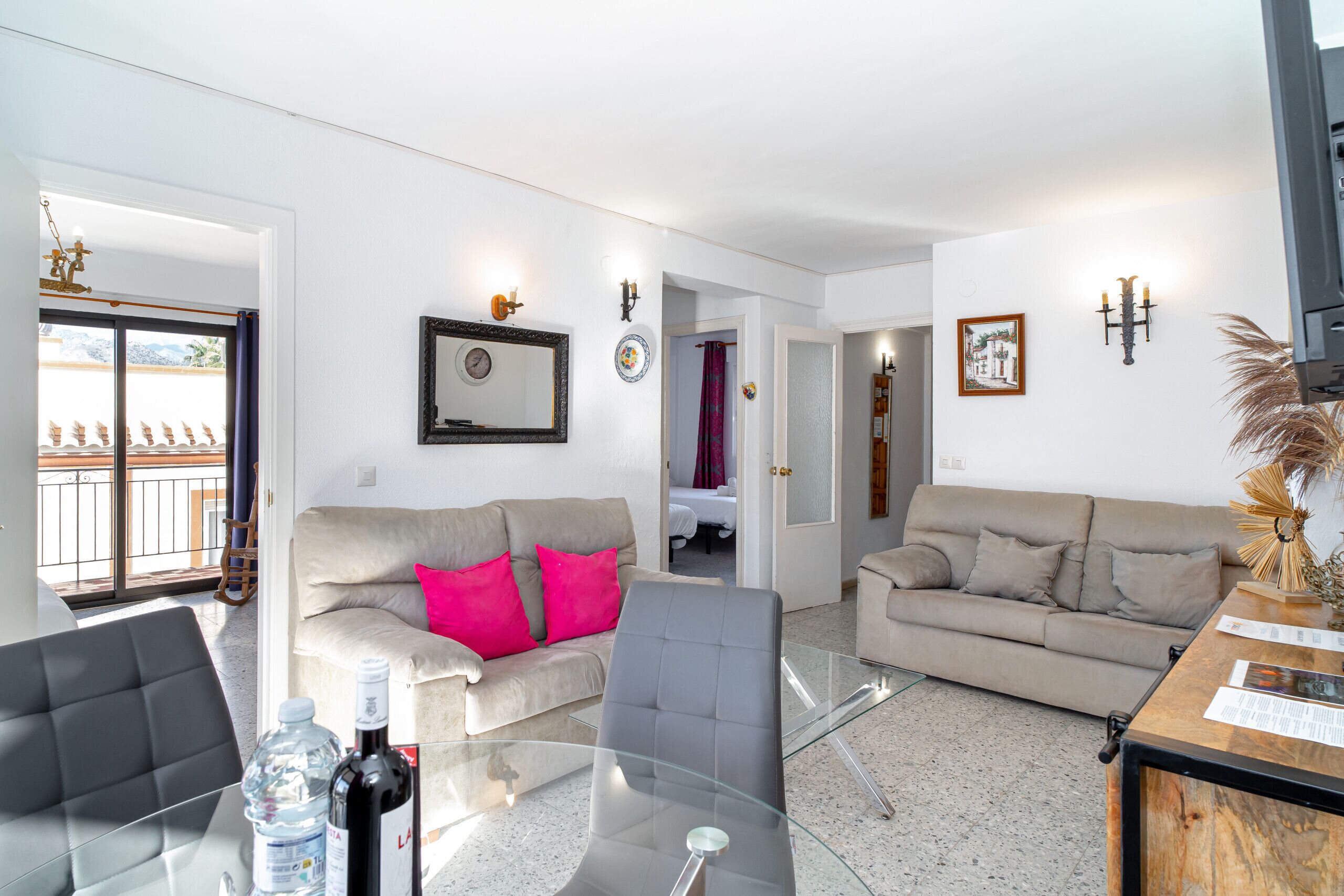 Una sala de estar moderna con dos sofás, una mesa de centro de cristal y un comedor con aparador de madera.
