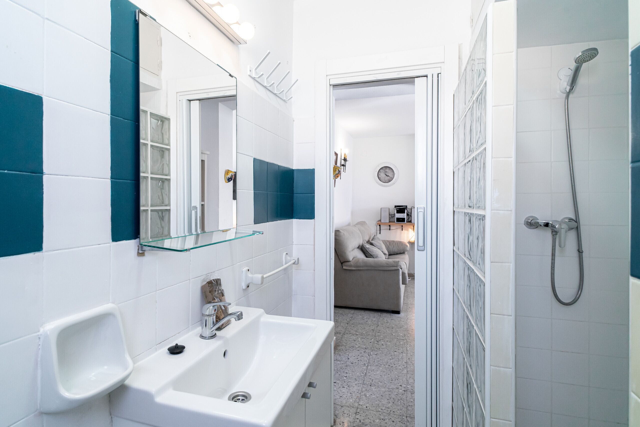 A modern bathroom with a white sink, mirror, and shower.