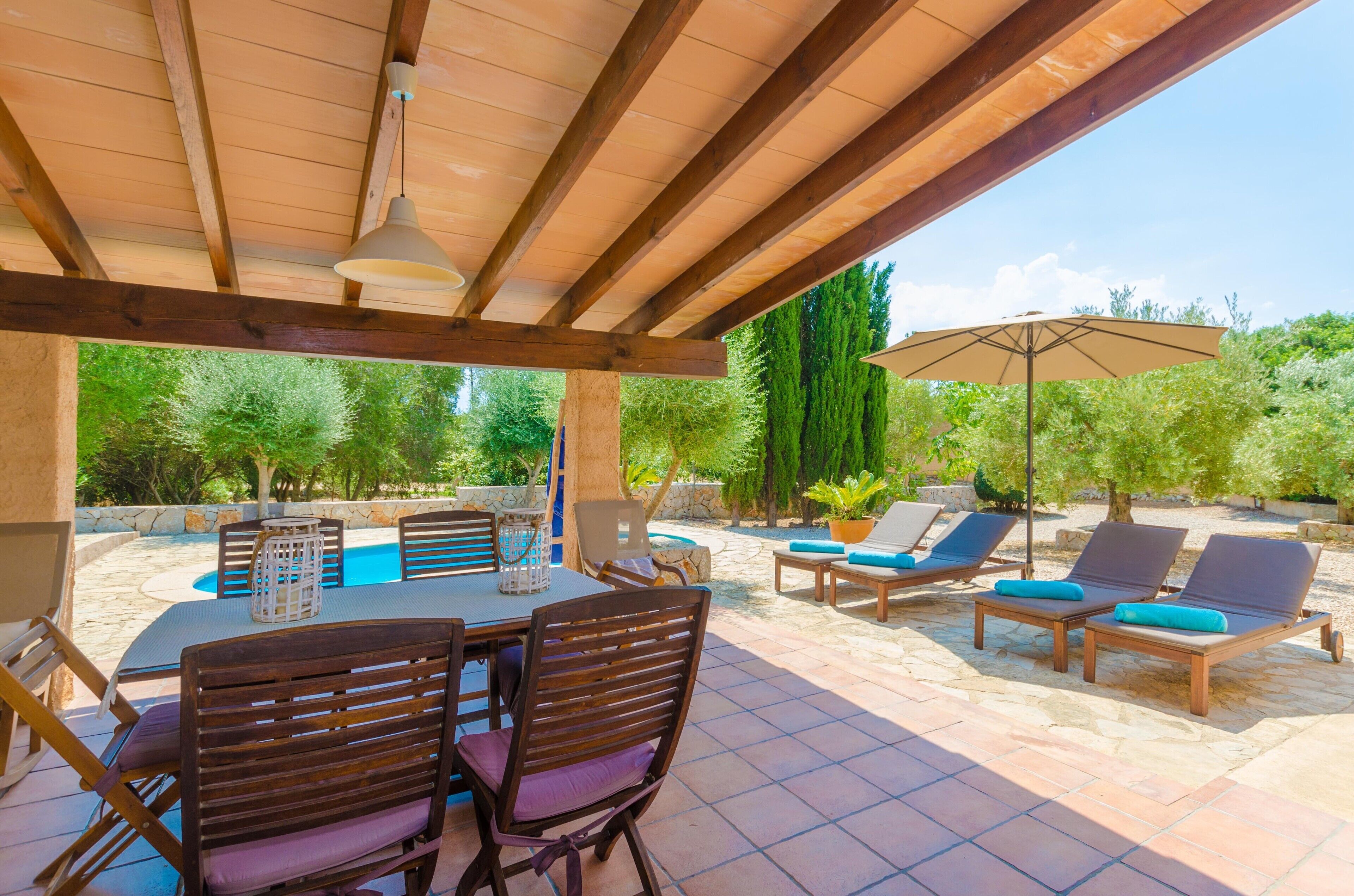 An outdoor patio with a pool table, lounge chairs, and a pergola.