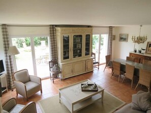 A spacious living room with a large cabinet, a dining area with a table and chairs, and a television on a stand.