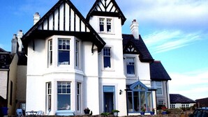 A two-story house with a stone wall in front, a bay window, and a conservatory.