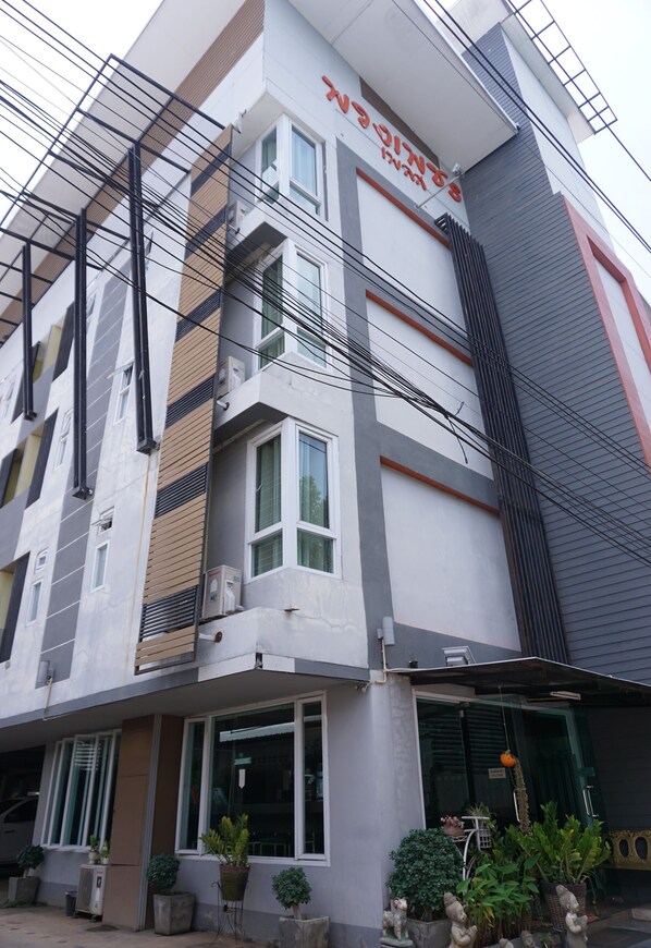 A multi-story building with a modern architectural design, featuring a mix of glass and metal elements, and a prominent entrance with potted plants.