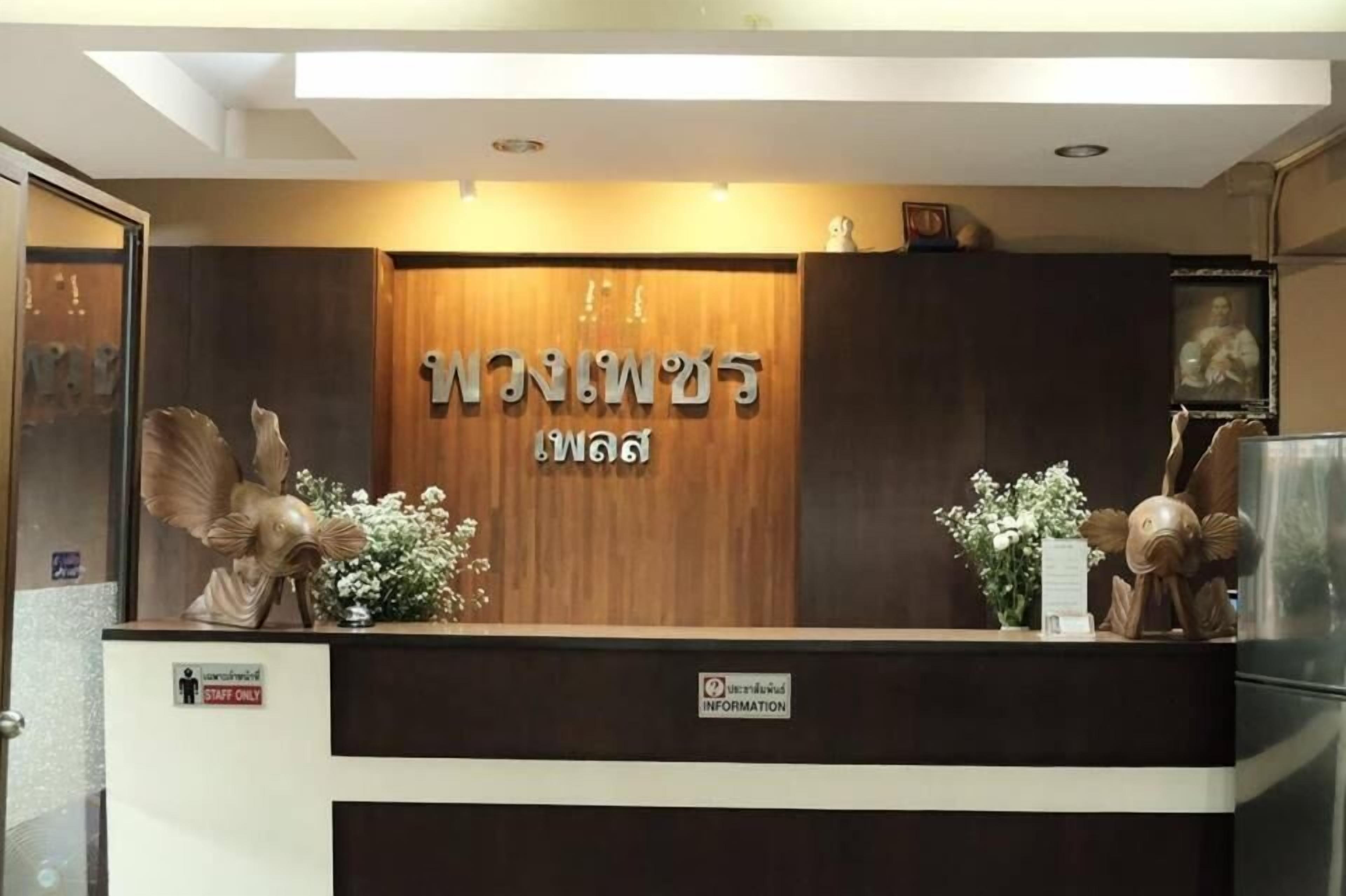 Un mostrador de recepción con un fondo de madera y el nombre "GEMINI" en grande. Hay esculturas decorativas y flores sobre el mostrador.