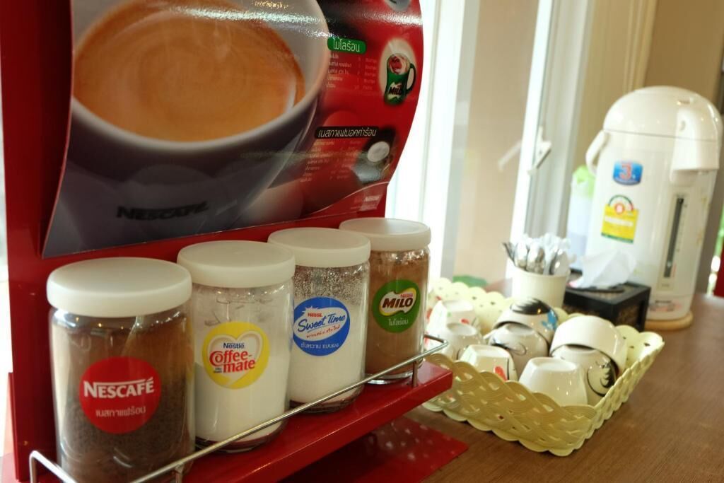 Una estación de café con un expositor de Nescafé, granos de café y una máquina de café.