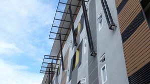 A multi-story building with a modern architectural design, featuring a combination of grey and wooden paneling, and a series of balconies with metal railings. - Puangpech Place (Lampang)