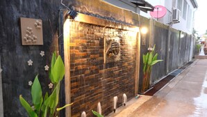 A brick wall with a water feature and plants. - Puangpech Place (Lampang)
