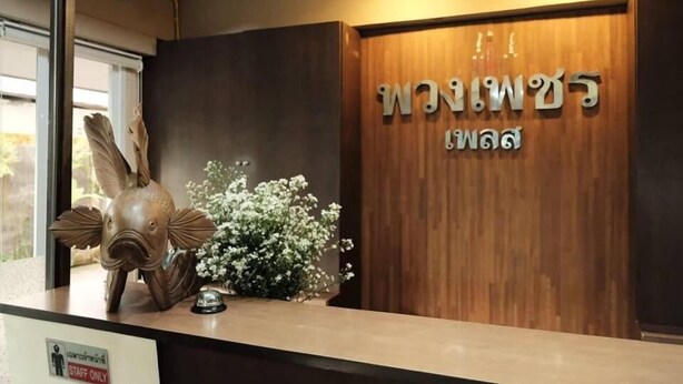 A reception desk with a wooden backdrop, a decorative fish sculpture, and a sign indicating 'Staff Only'. - Puangpech Place (Lampang)
