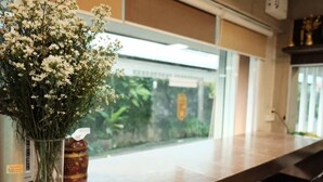 A room with a clear view of the outdoors, a window, and a table with a vase of flowers. - Puangpech Place (Lampang)