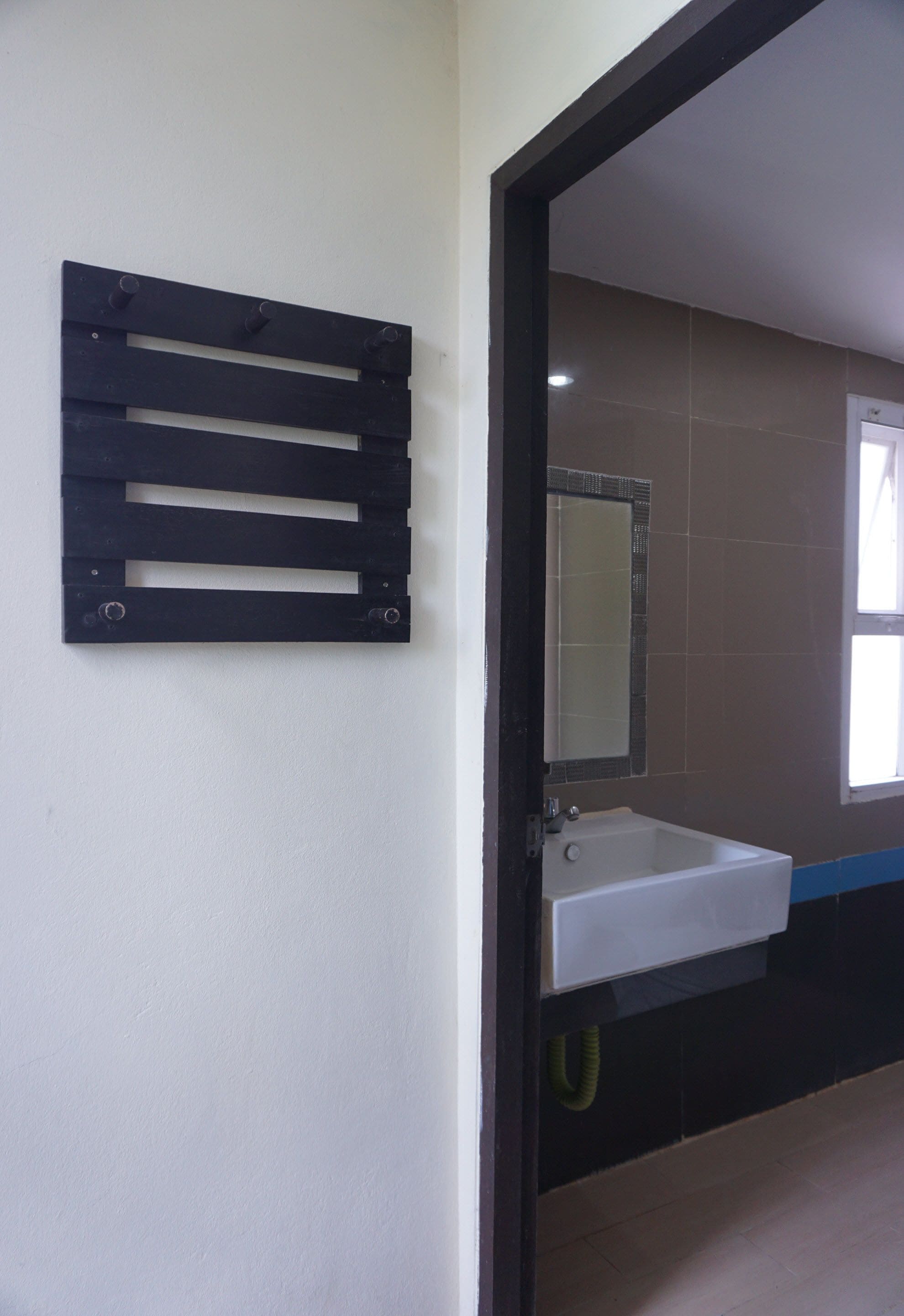A bathroom with a white sink, a mirror, and a black towel rack.
