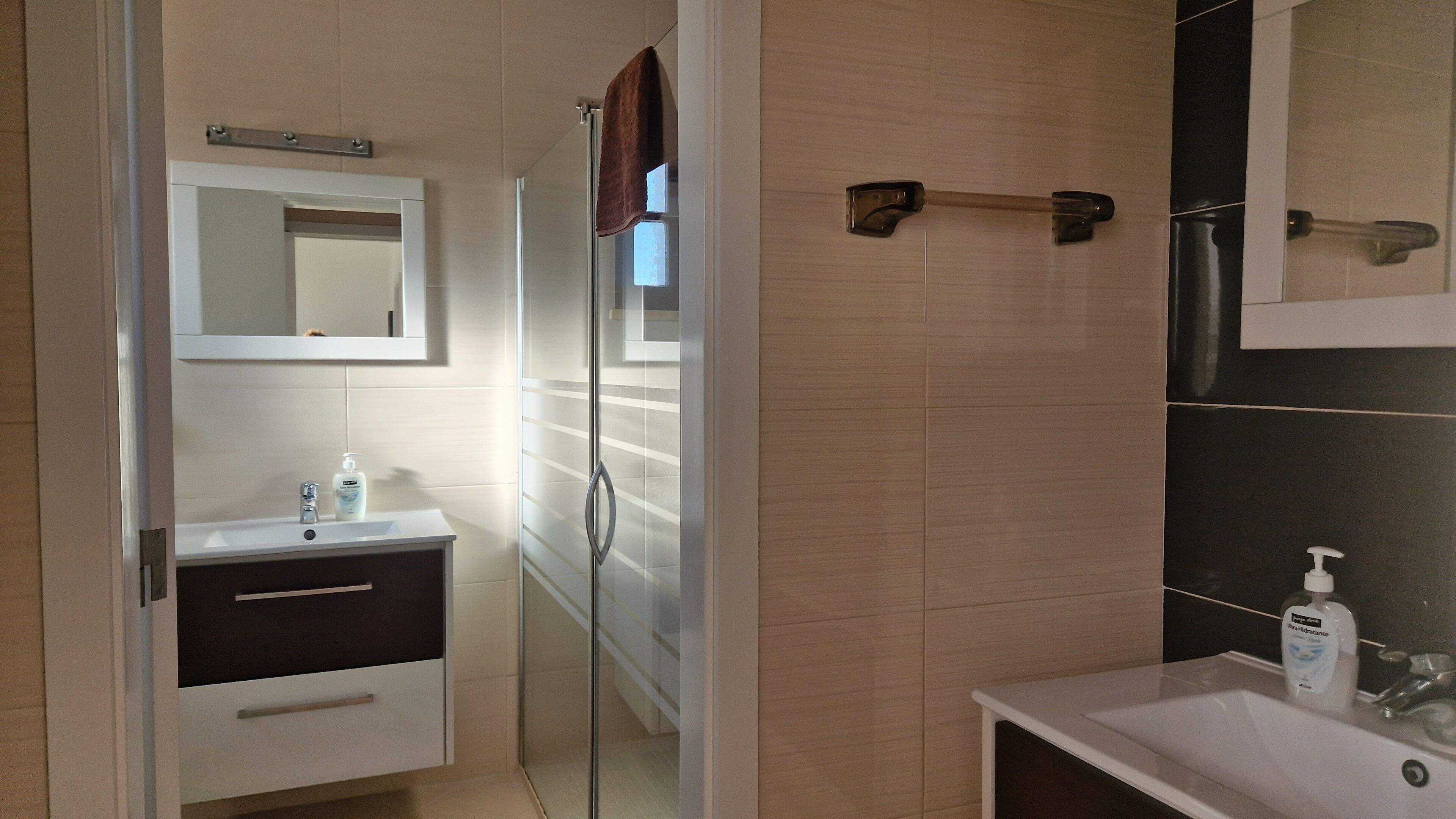 A modern bathroom with a glass shower door, a white sink, and a mirror above the sink.