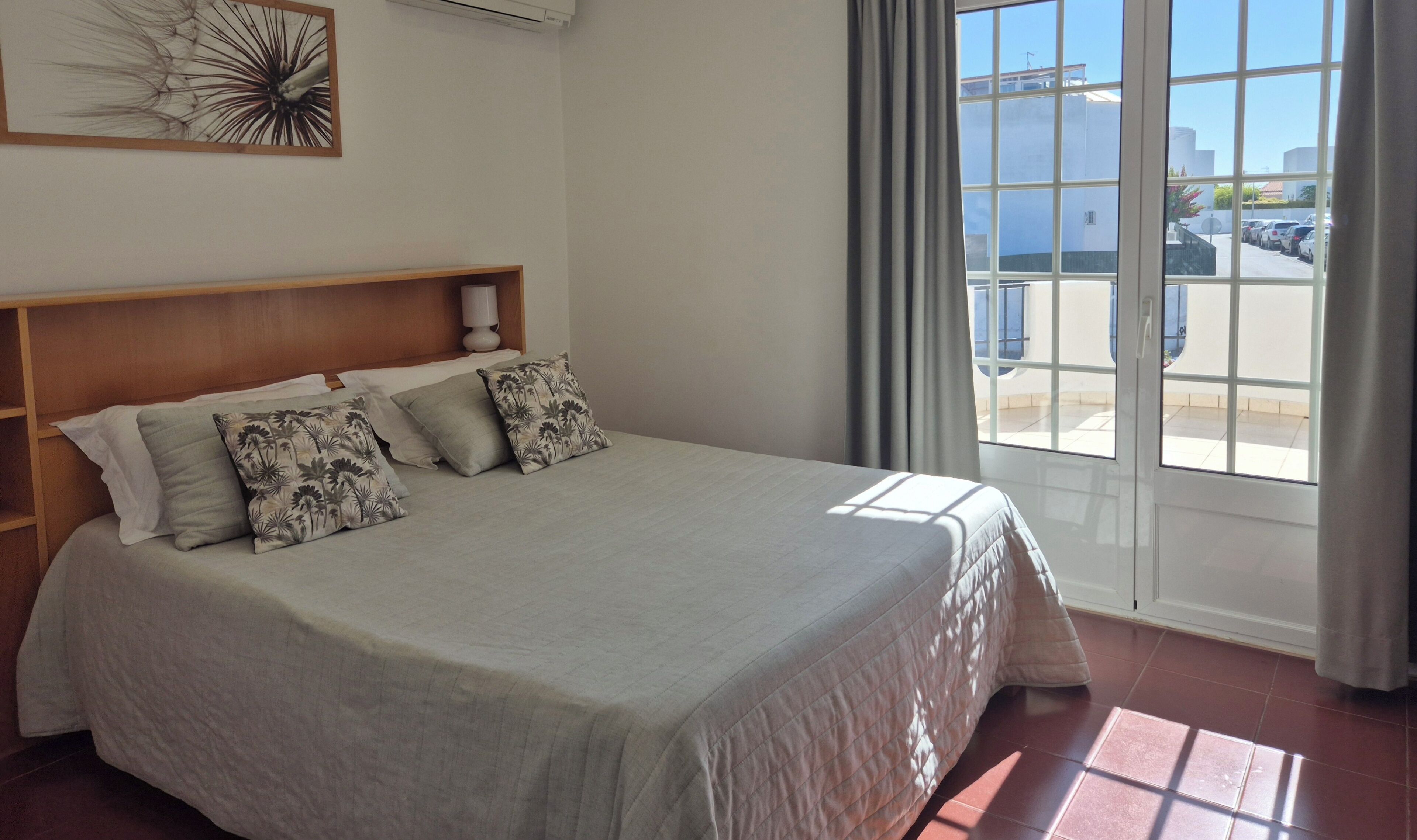 Habitación de hotel con cama, cabecera, obra de arte colgada en la pared y vistas al exterior.