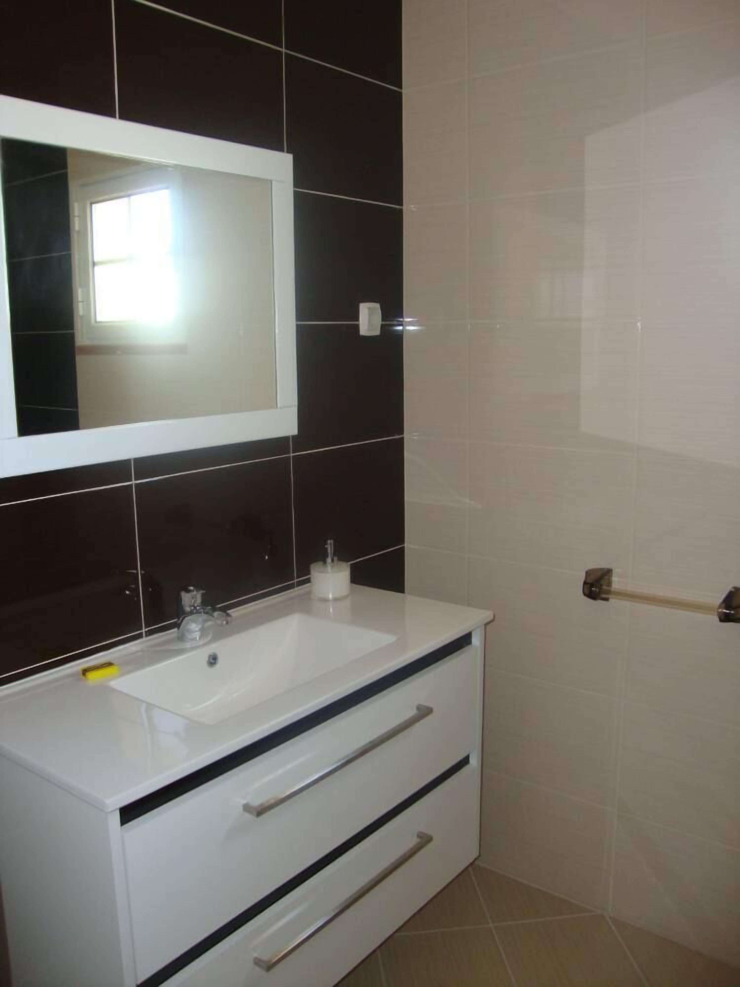 A bathroom with a white sink, a mirror, and a towel rack.