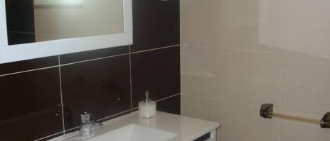 A bathroom with a white sink, a mirror, and a towel rack.